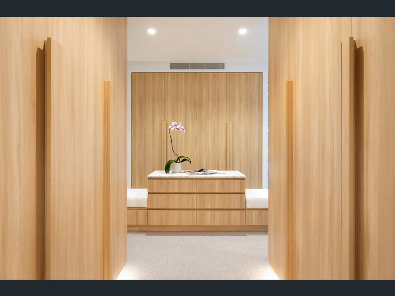Timber walk-in robe with island drawers and styled orchid