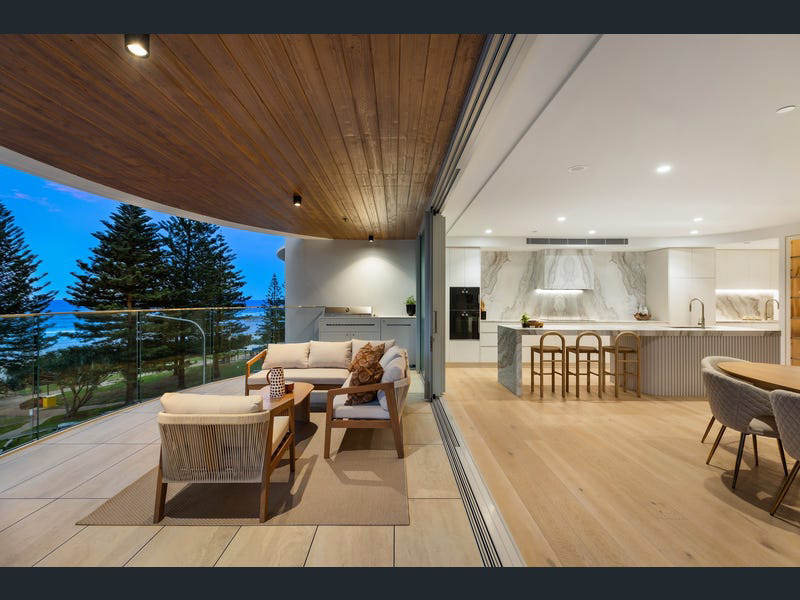 Oceanfront outdoor deck with lounge seating opening to the marble kitchen at 402/154 Marine Parade