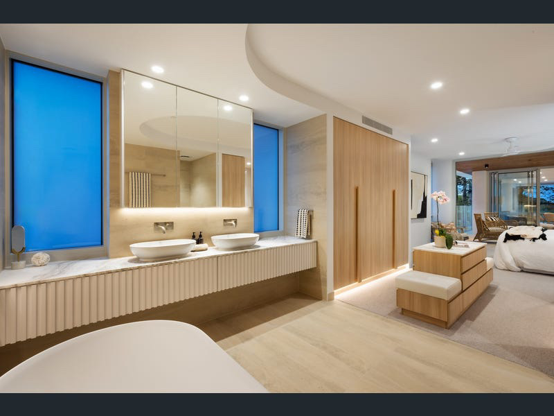 Dual-vanity ensuite with freestanding tub, fluted joinery and stone benchtop