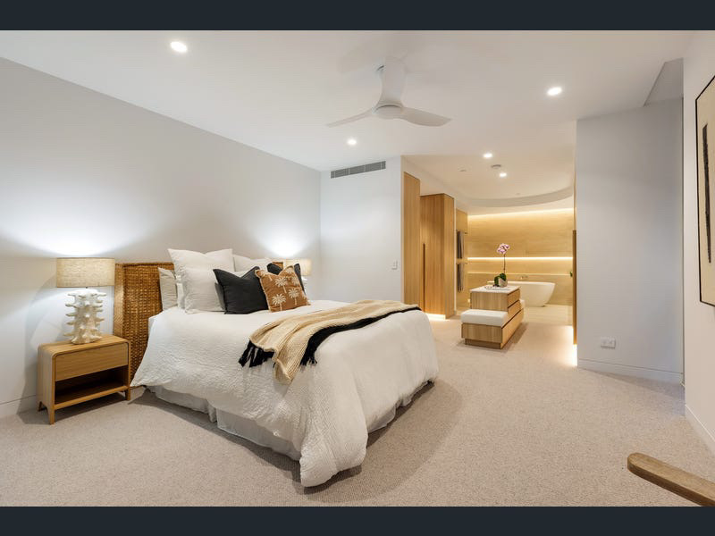 Master bedroom with rattan bedhead opening through to the curved timber ensuite