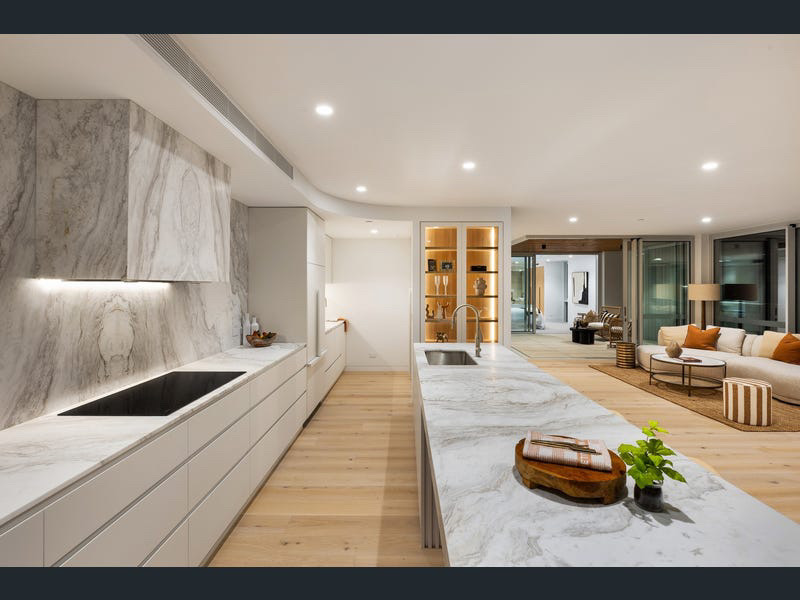 Galley view of the marble kitchen looking through to the styled living room