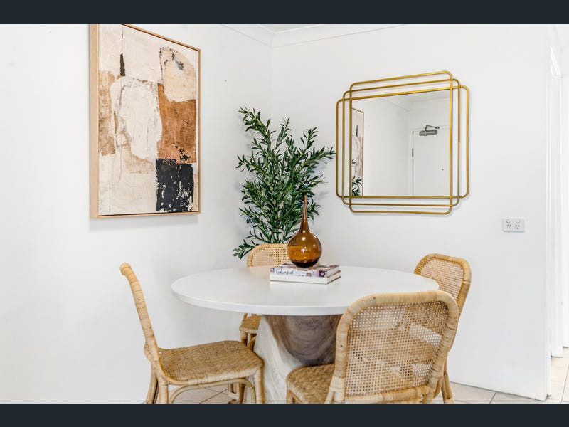 Dining nook with round table, cane chairs, abstract artwork and gold mirror
