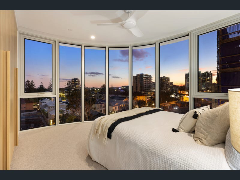 Master bedroom with curved floor-to-ceiling windows and dusk skyline view