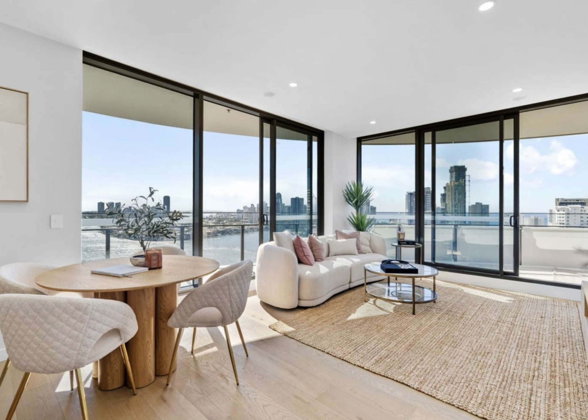 Styled open-plan living and dining space with river and skyline views at Chevron One