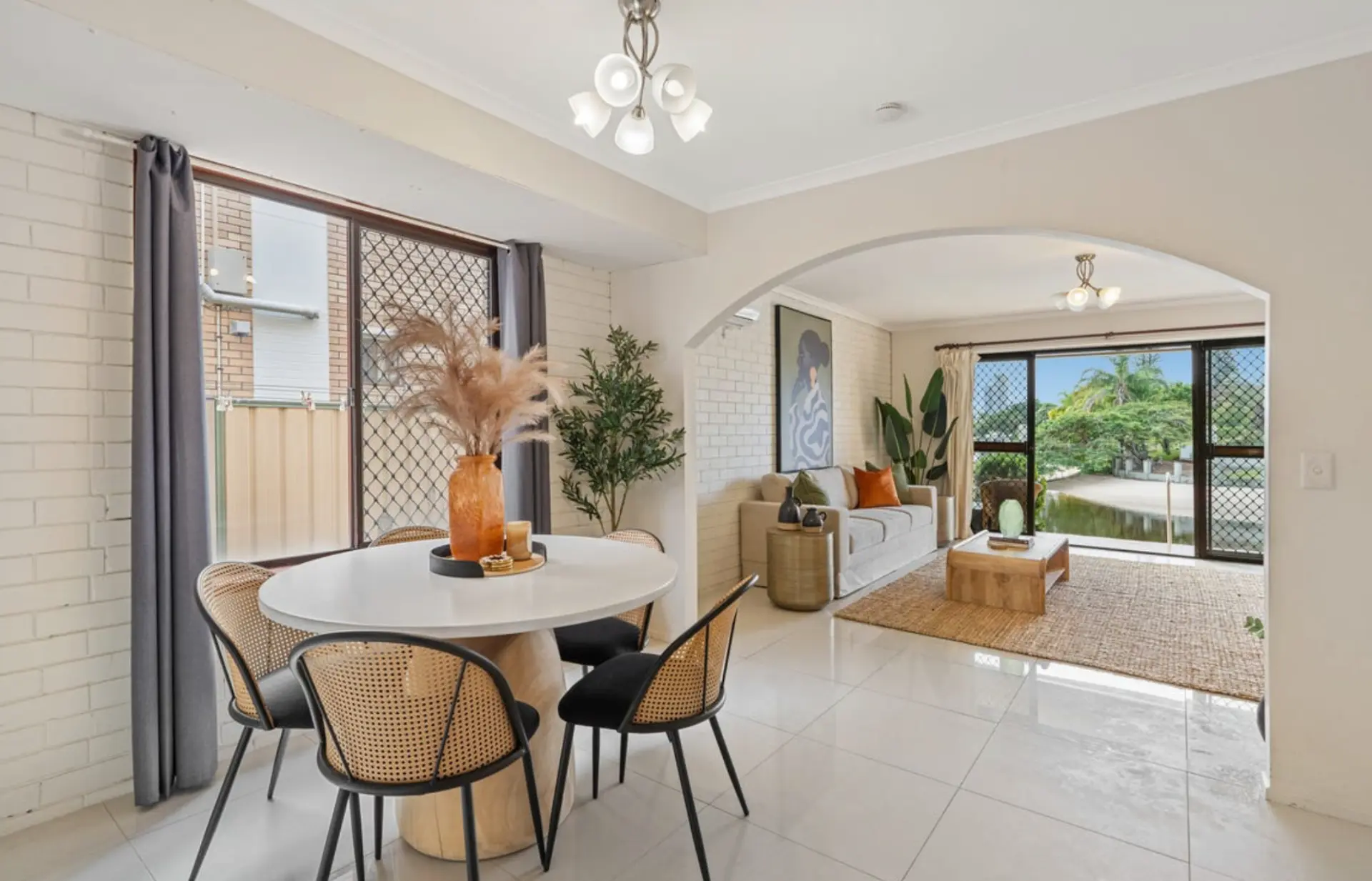 Round dining table with cane chairs and pampas styling beside the living zone