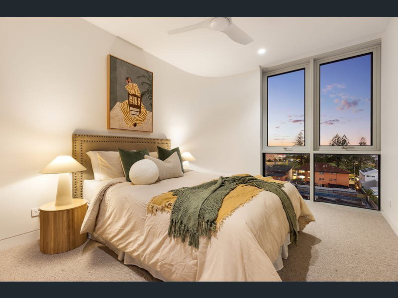 Second bedroom styled with olive and mustard linens and framed artwork