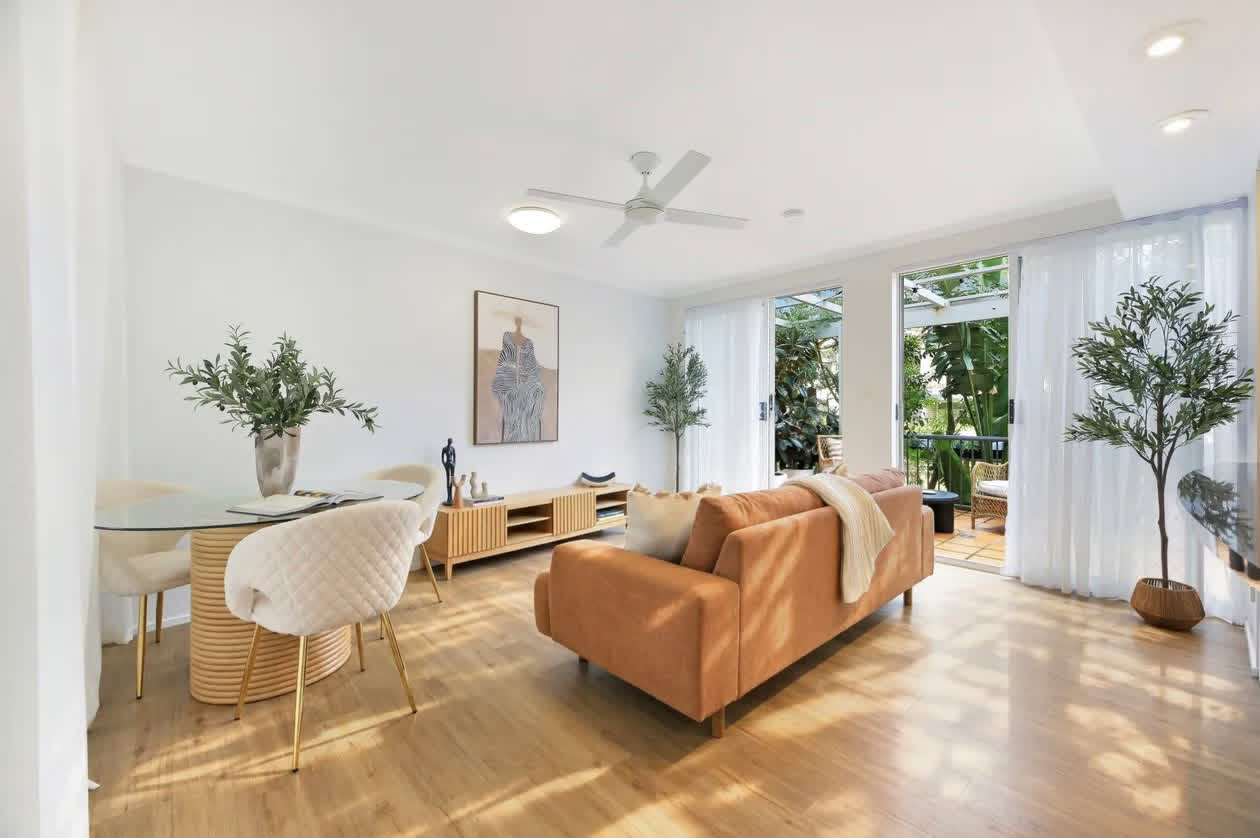 Sunlit open-plan living and dining room with terracotta sofa at 3/100 Petrel Avenue, Mermaid Beach