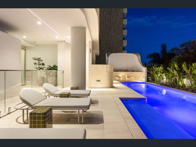 Resort lap pool and sun lounges lit at dusk