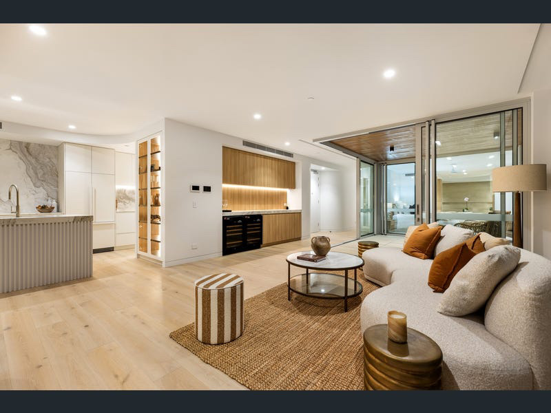 Open-plan living room with bouclé sofa, jute rug and timber joinery opening to the terrace