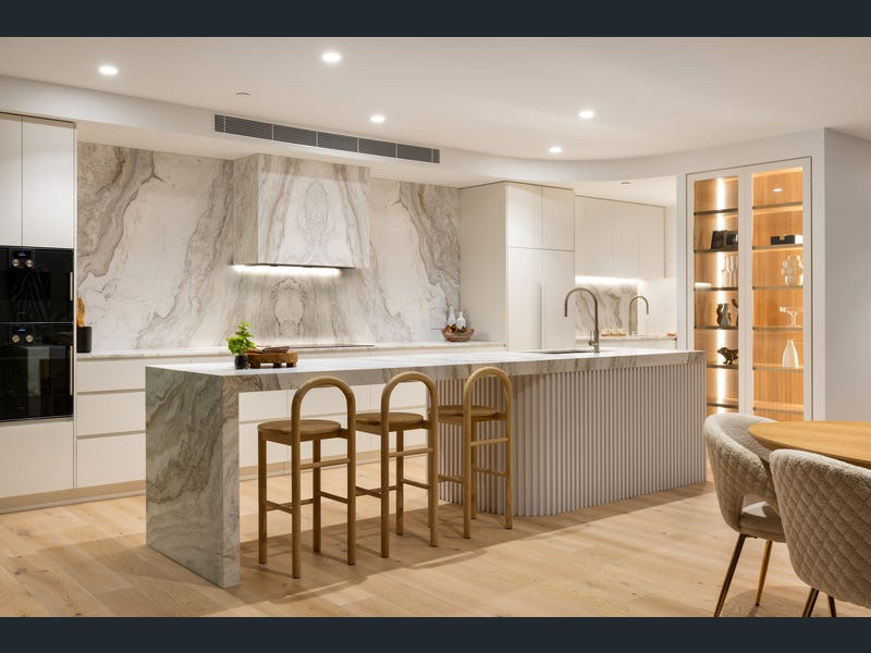 Kitchen and dining zone with sculptural marble splashback and boucle chairs