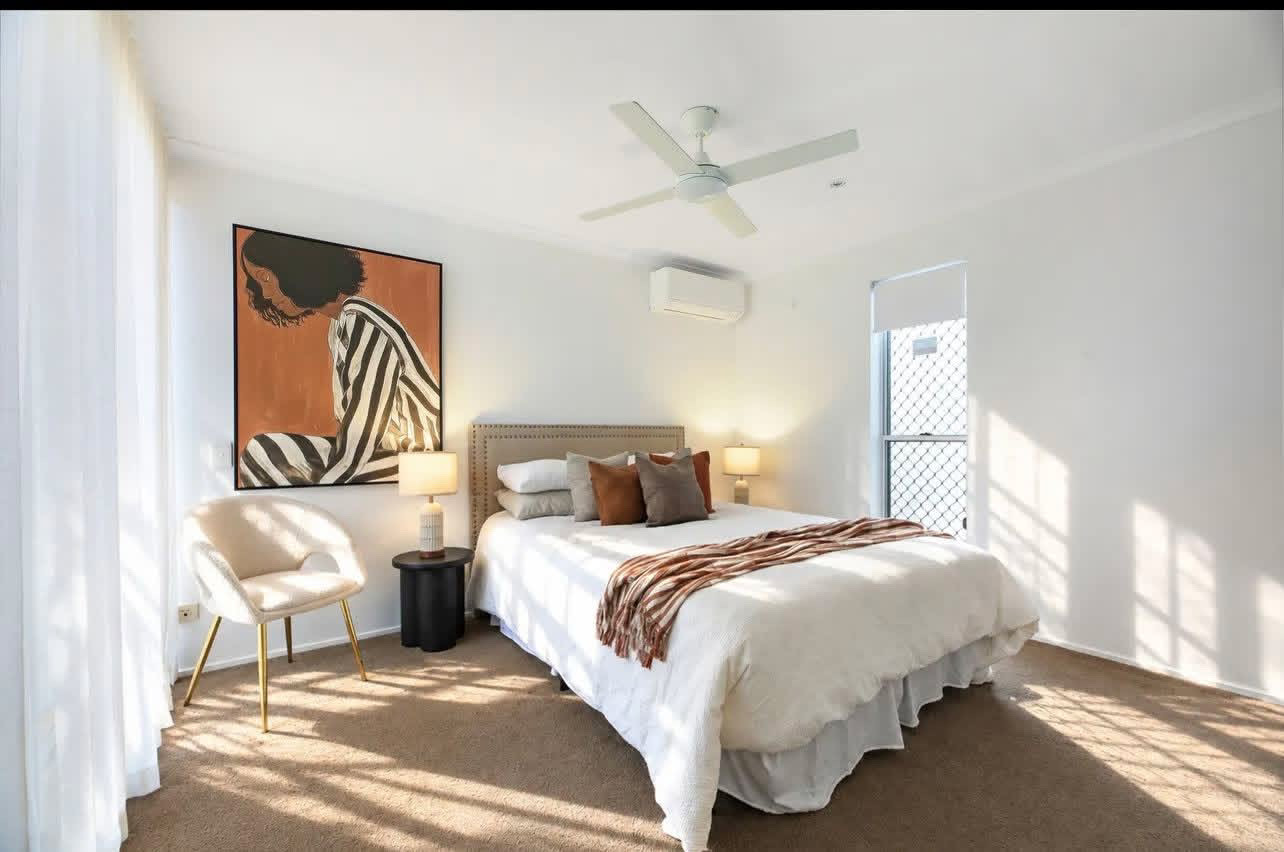 Master bedroom with white linen, striped throw and terracotta artwork