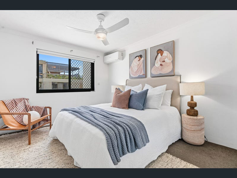 Bedroom styled with white linen, blue throw and paired figurative artworks