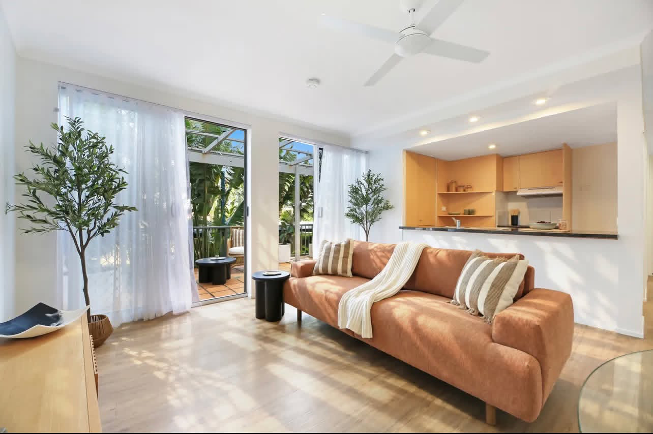 Living room with terracotta sofa and sheer curtains opening to the balcony