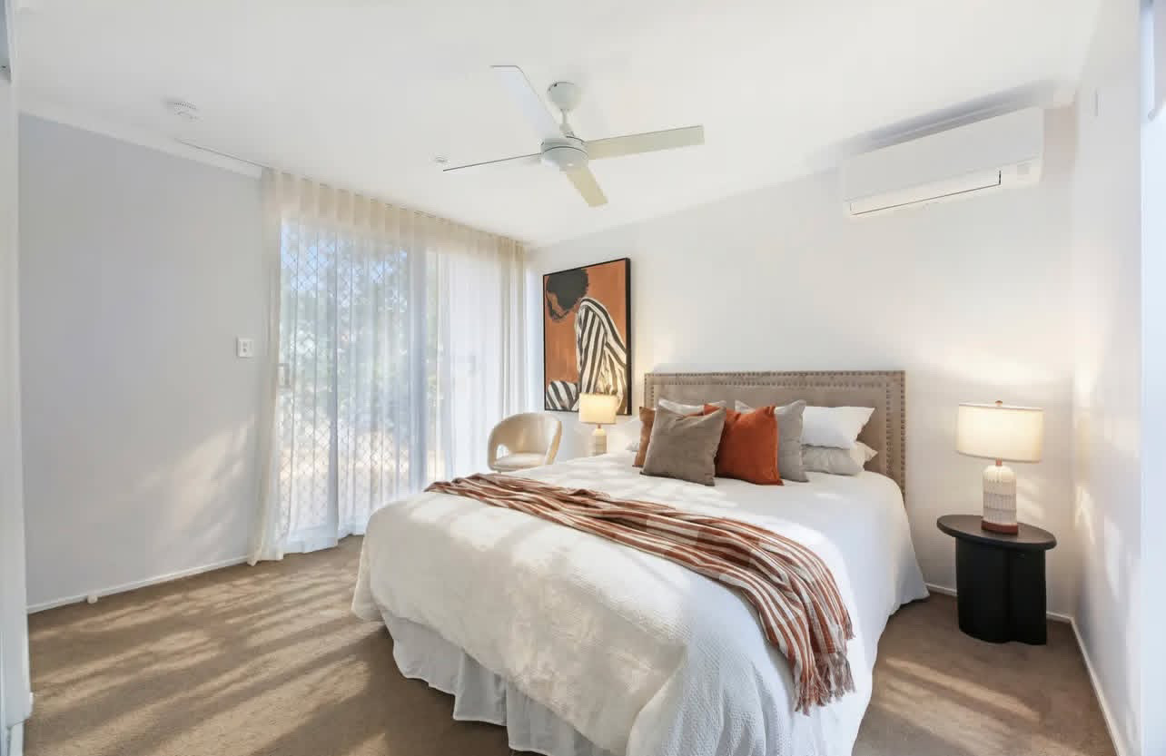 Second bedroom styled with rust and linen cushions and woven throw