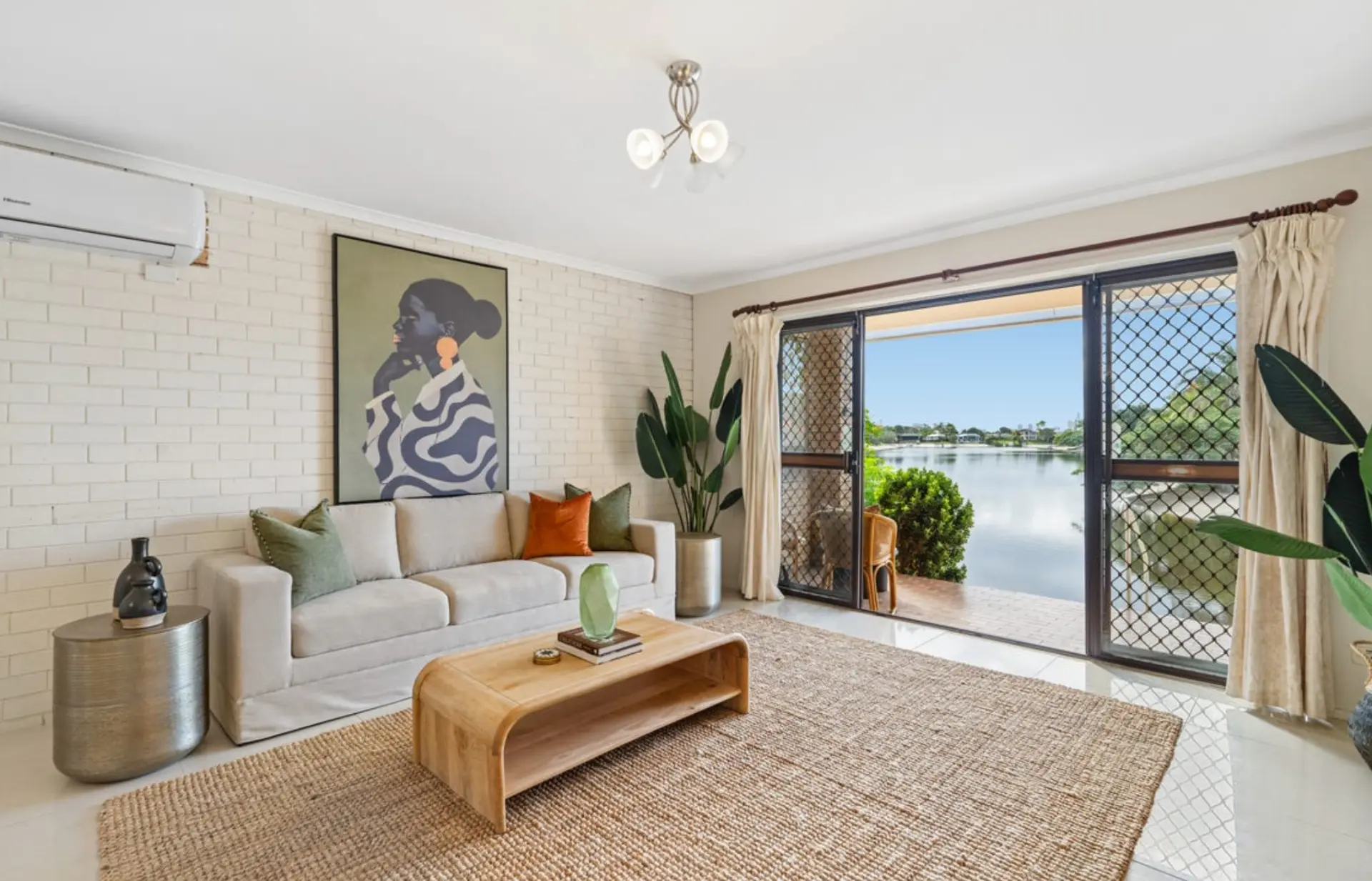 Waterfront living room styled with a linen sofa, jute rug and framed artwork at Mermaid Waters