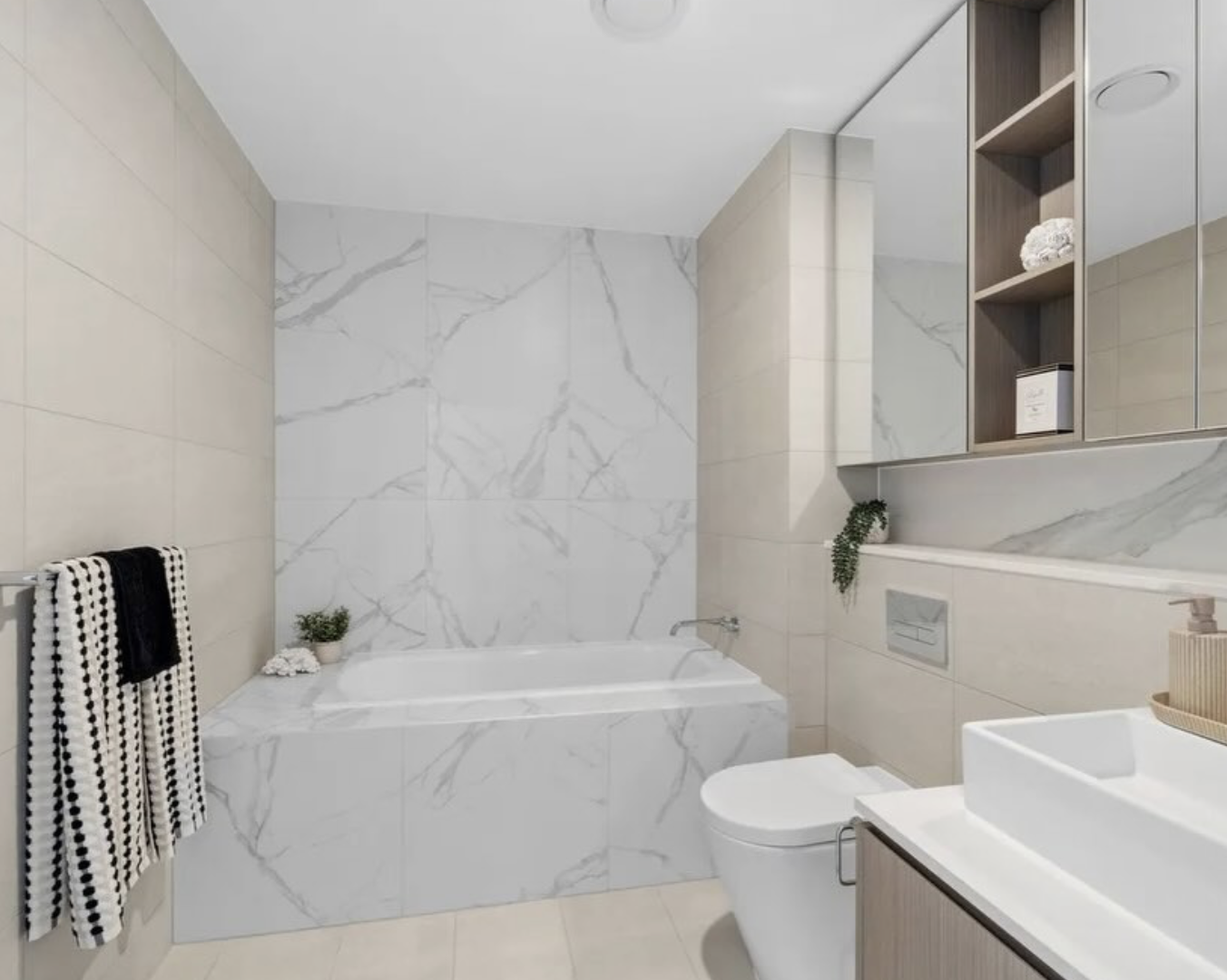 Main bathroom in marble with built-in bath and styled towels